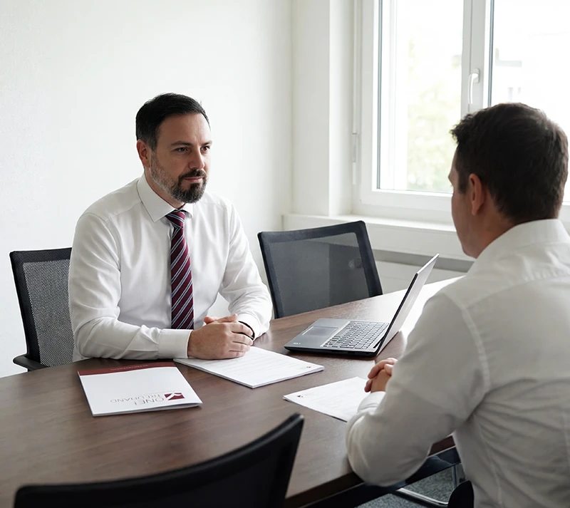 In einem modernen Büro diskutieren zwei Fachleute detailreich über Steuern und die optimale Treuhandstrategie.